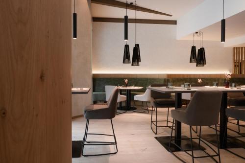 a dining room with tables and chairs and pendant lights at Neueröffnung ELVA PREMIUM APARTMENT HOTEL inklusive Sommerpass STUBAI SUPER CARD in Neustift im Stubaital