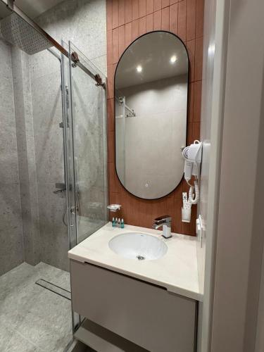 a bathroom with a sink and a shower with a mirror at Bugu Hotel Bishkek in Bishkek