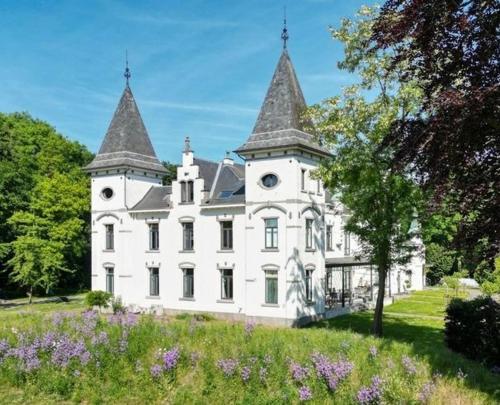 a large white building with two towers on top of a field at Vakantiewoning de Toren in Kortessem