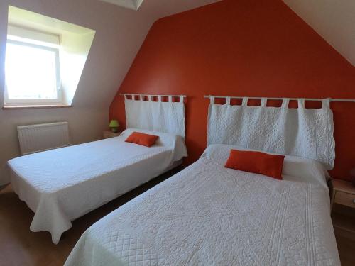 - 2 lits dans une chambre aux murs rouges dans l'établissement Ti Penn Gite de Saint Guénolé, à Trévou-Tréguignec
