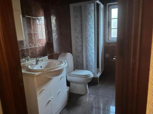 un bagno con lavandino, WC e finestra di D Lina Alojamento Local a Trancoso