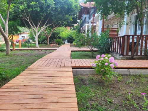 a wooden walkway in a park with flowers at Yedi Butik Hotel in Kemer