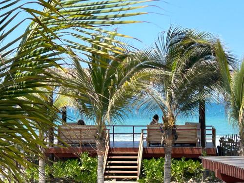two people sitting on benches looking at the ocean at El Samay Hotel Boutique in Canoas De Punta Sal