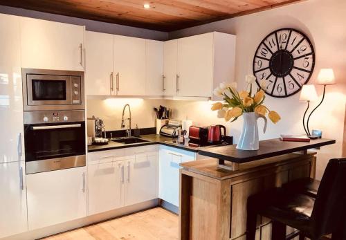 une cuisine avec des placards blancs et une horloge murale dans l'établissement One Le Savoy French Alps - vacation apartment, à Chamonix-Mont-Blanc