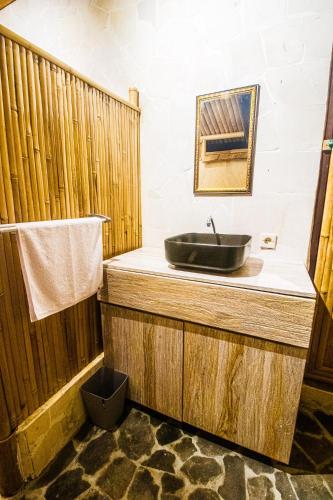a bathroom with a sink on a wooden counter at Uma D Mapad Sidemen in Sidemen