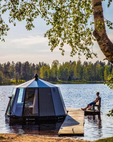 a man sitting on a bench on a dock in a lake at Tackork Gård & Marina in Nauvo