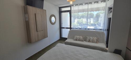 ein Schlafzimmer mit einem Bett, einem Fenster und einer Couch in der Unterkunft Studio cv, parking, plage 5 mn in La Grande-Motte