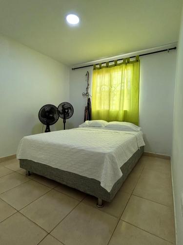 a bedroom with a large bed with a yellow curtain at Encantadora casa guajira 1 in Barranquilla