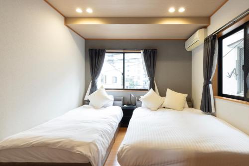 two beds in a room with a window at Chiyo House x M&Z HOUSE in Fukuoka