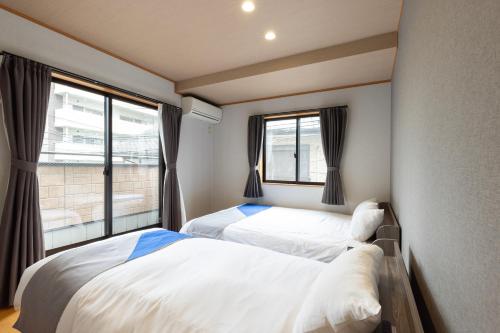 two beds in a room with two windows at Chiyo House x M&Z HOUSE in Fukuoka