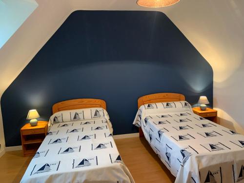 - 2 lits dans une chambre avec un mur bleu dans l'établissement Ti Bihan Gite de Saint Guénolé, à Trévou-Tréguignec