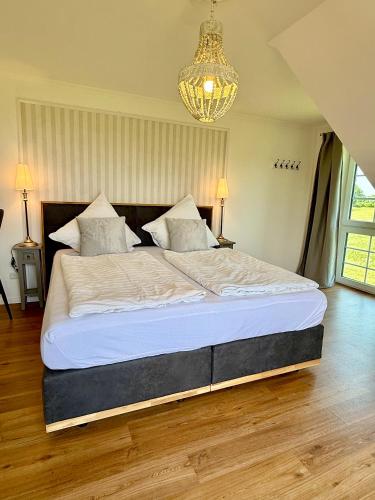 a large bed in a bedroom with a chandelier at Hasselberger Huus in Hasselberg