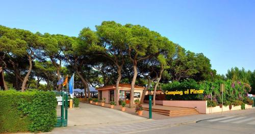 a park with a bench and trees and a building at Camping Alannia El Pinar in Blanes