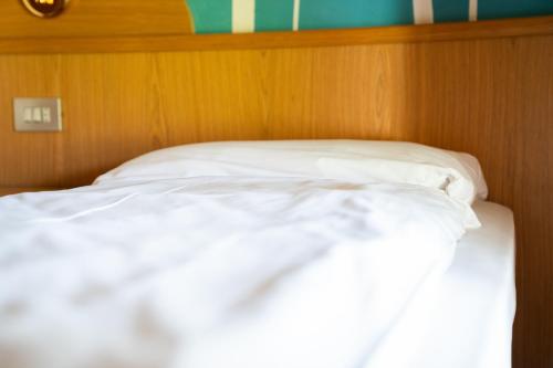 a bed with white sheets and a wooden head board at Enrosadira in Predaia