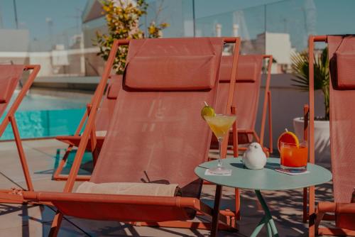 a table with a drink and two chairs next to a pool at Vincci Molviedro in Seville