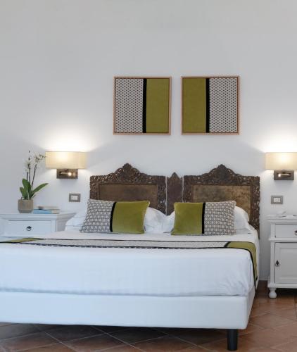 a bedroom with a white bed with green and white pillows at Hotel Cala Caterina in Villasimius