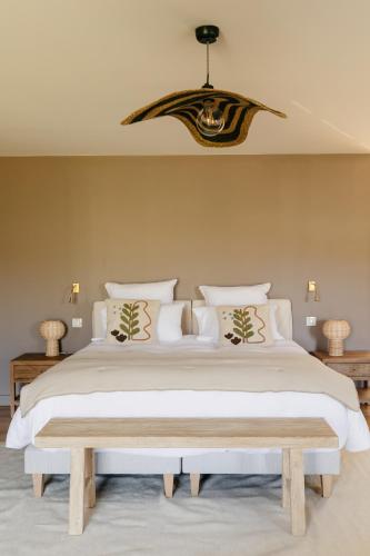 une chambre avec un grand lit blanc et un lustre dans l'établissement Mas de l'Etoile, à Aureille