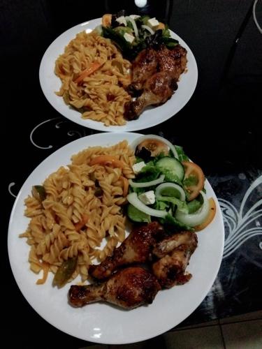 two plates of food with chicken and noodles and vegetables at Sunshinevibe guest house in Kasane