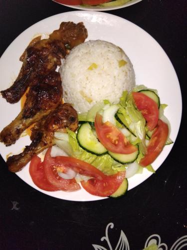 a plate of food with chicken and rice and vegetables at Sunshinevibe guest house in Kasane