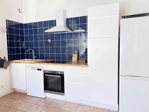 Il comprend une cuisine avec des placards blancs et un mur carrelé bleu. dans l'établissement ABYS Logement avec grande terrasse, à Saint-Martin-de-Ré