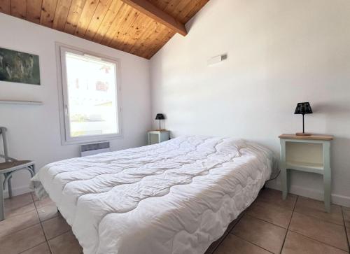 une chambre avec un grand lit blanc avec une fenêtre dans l'établissement ABYS Logement avec grande terrasse, à Saint-Martin-de-Ré