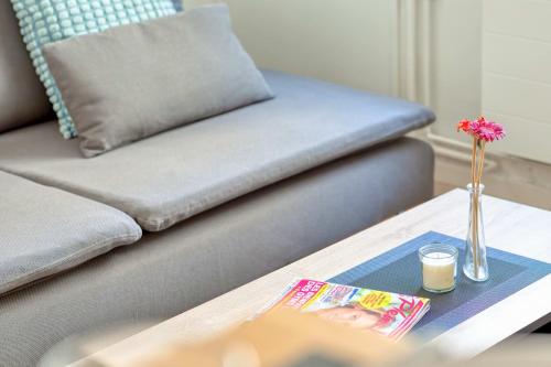une table basse avec un canapé et un vase avec une fleur dessus dans l'établissement Le Alain charmant duplex au cœur de Rouen, à Rouen