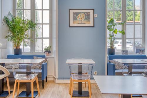 a restaurant with tables and chairs and windows at Hôtel François 1er in La Rochelle