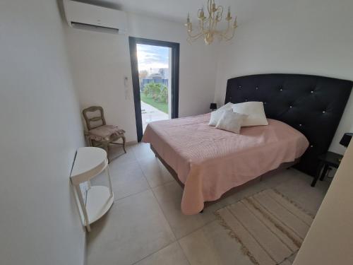 une chambre avec un lit, une chaise et une fenêtre dans l'établissement La villa Dorée, à Sérignan