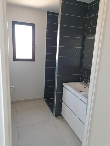une salle de bain avec un lavabo blanc et une fenêtre dans l'établissement La villa Dorée, à Sérignan