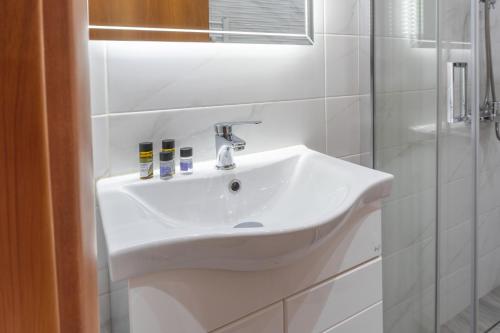 a bathroom with a white sink and a shower at Helen's Little Castle free private parking in Thessaloniki