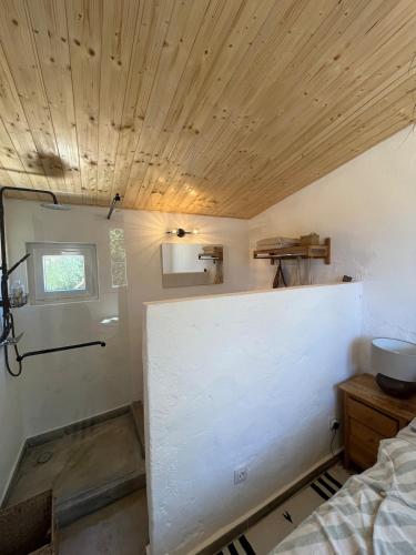 a room with a white wall and wooden ceiling at Rustic cabin with pond and deck in Aljezur