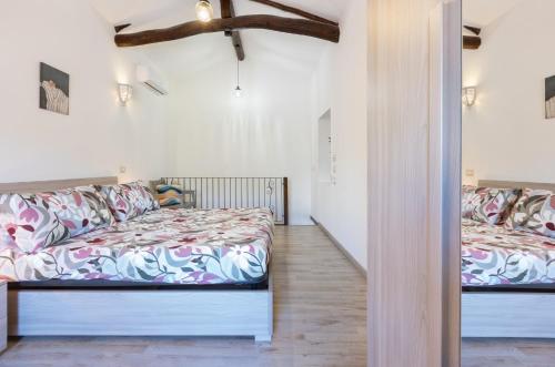 two beds in a room with white walls and wood floors at GuestHost - My Little Pink House in Selargius