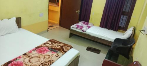 a room with two beds and a chair in it at Rathore Inn in Hāora