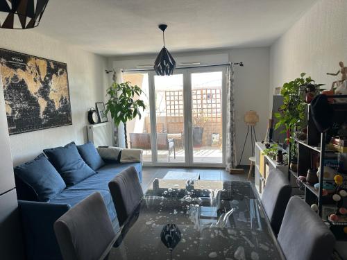 un salon avec un canapé bleu et une table en verre dans l'établissement résidence proche de la mer, à Port-de-Bouc