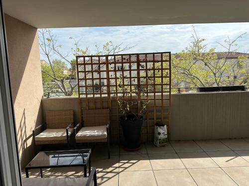 - un balcon avec deux chaises et une plante en pot dans l'établissement résidence proche de la mer, à Port-de-Bouc