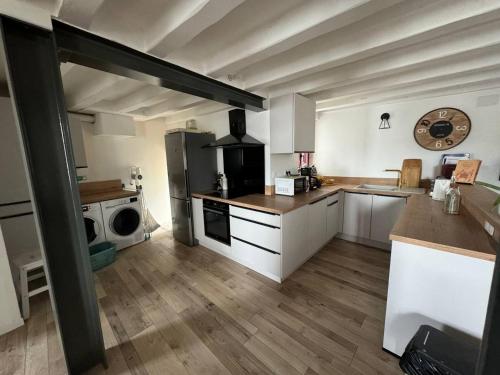 Il comprend une grande cuisine avec des placards blancs et un réfrigérateur. dans l'établissement Maison familiale proche Thermes, Lac et Plages, à Saujon