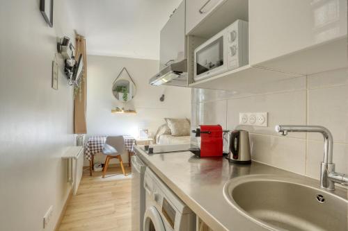 une cuisine avec un évier et un salon dans l'établissement Le Lully - Versailles, à Versailles