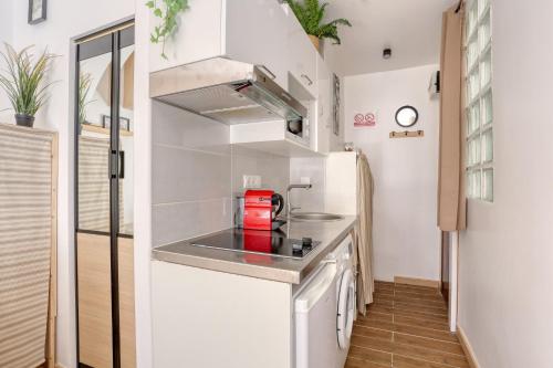 une petite cuisine avec un évier et un réfrigérateur dans l'établissement Le Lully - Versailles, à Versailles