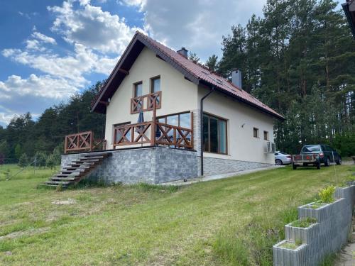 a small white house with a grass field at Na Skraju Lasu 