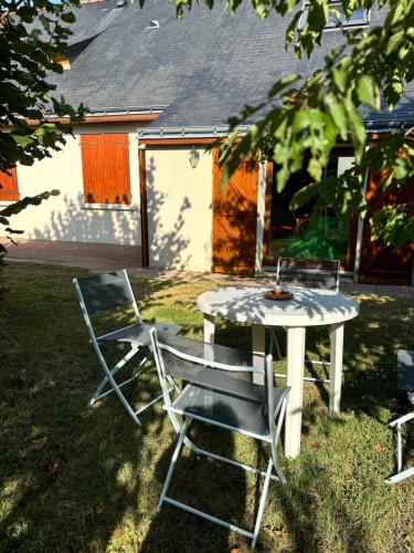 2 chaises, une table, une table et des chaises dans l'établissement Chez Raoul, maison agréable, à Villebernier