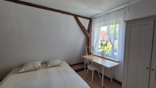 a bedroom with a bed and a desk and a window at Apartament LUA in Ustka