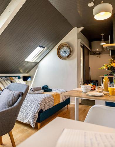 Cette chambre comprend un lit et une table avec une horloge. dans l'établissement Agréable cocon sous les toits - Parking - WiFi, à Pléneuf-Val-André