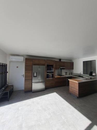 une grande cuisine avec des placards en bois et des appareils en acier inoxydable dans l'établissement Maison de plain-pied 3 chambres classée 4 étoiles dans impasse au calme, à La Guérinière