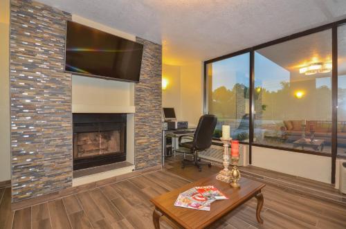 a living room with a fireplace with a flat screen tv at Days Inn by Wyndham Southern Hills/ORU in Tulsa