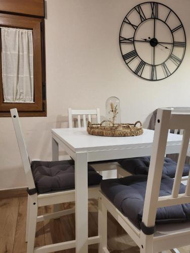 a white dining room table with two chairs and a clock at El Casillo de Gredos in Navacepeda de Tormes