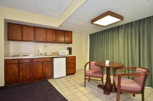 a kitchen with a table and chairs and a table and a kitchen with a counter at Days Inn by Wyndham Southern Hills/ORU in Tulsa