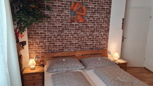 a bedroom with two beds and a brick wall at Urlaubsnest in Harbach