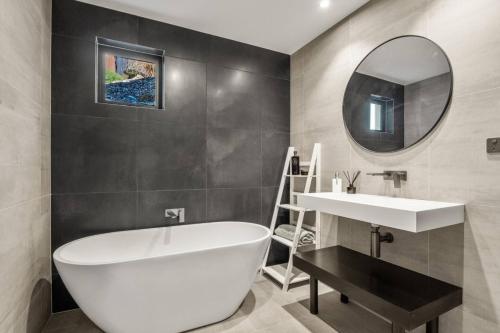 un bagno con vasca, lavandino e specchio di The Middleton Room a Queenstown