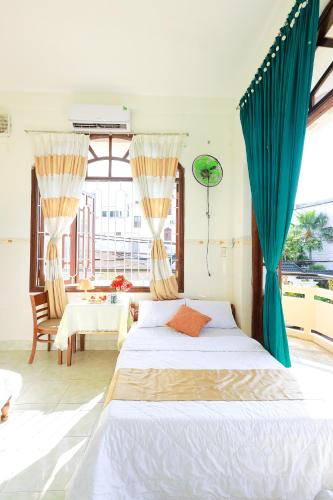 a bedroom with a bed with blue curtains and a table at Hotel Ngọc My in Phan Thiet