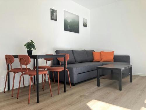 Una sala de estar con un sofá, una mesa y sillas. en Spacious Apartment for 3, en Odense
